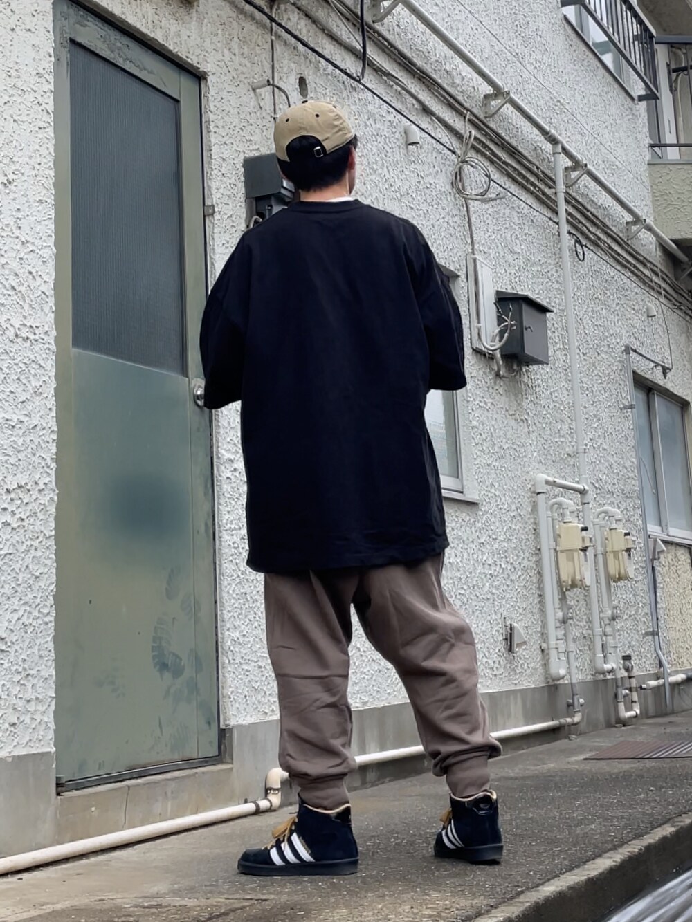 ブラック系のスニーカー、ブラウン系のパンツ、ブラック系のTシャツ/カットソーを着用したメンズの春コーディネートの2枚目の写真