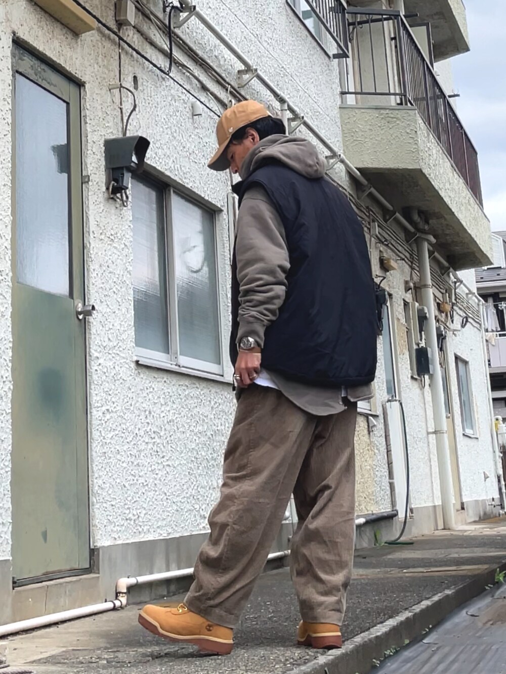 ブラック系のベスト、ベージュ系のその他パンツ、ベージュ系のパーカーを着用したメンズの秋コーディネートの2枚目の写真
