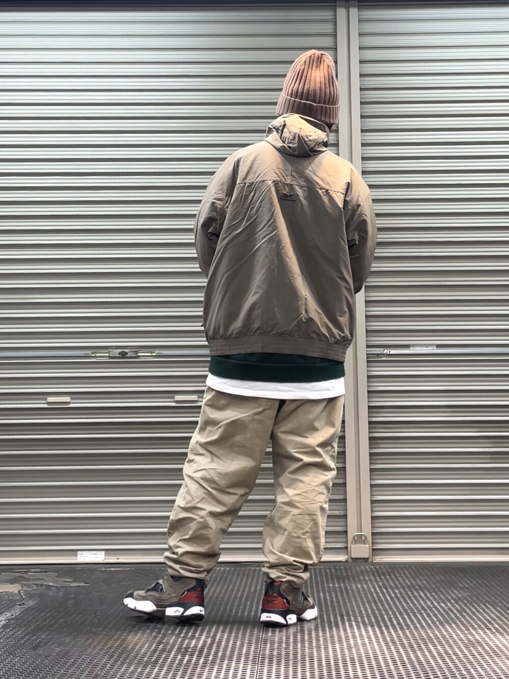 グレー系のスニーカー、ベージュ系のチノパンツ、グレー系のブルゾンを着用したメンズの冬コーディネートの2枚目の写真