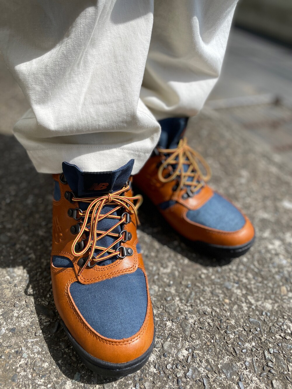 ブラウン系のスニーカー、ホワイト系のチノパンツ、ブラック系のベストを着用したメンズの春コーディネートの3枚目の写真