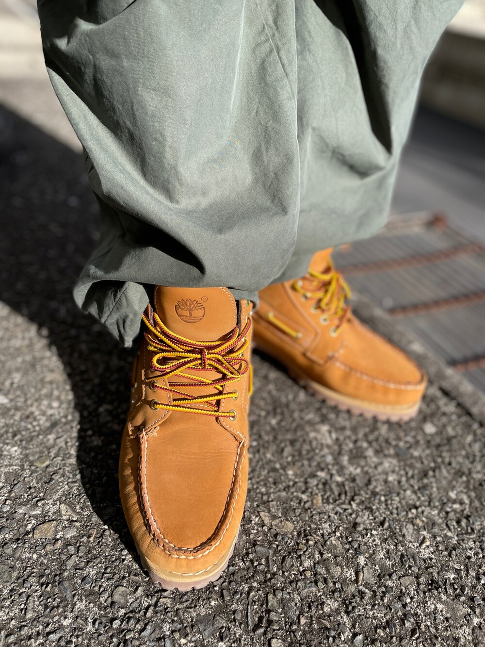 イエロー系のブーツ、グリーン系のパンツ、ブラック系のパーカーを着用したメンズの冬コーディネートの3枚目の写真