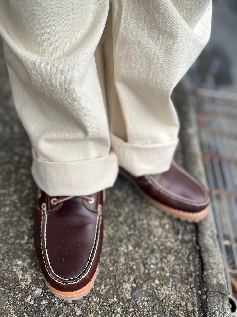 ブラウン系のニット/セーター、ブラウン系のモカシン/デッキシューズ、ホワイト系のパンツを着用したメンズの春コーディネートの3枚目の写真