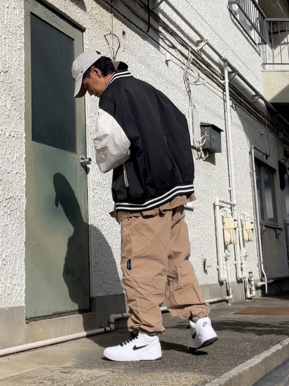 ホワイト系のスニーカー、ベージュ系のその他パンツ、ブラック系のスタジャンを着用したメンズの秋コーディネートの2枚目の写真