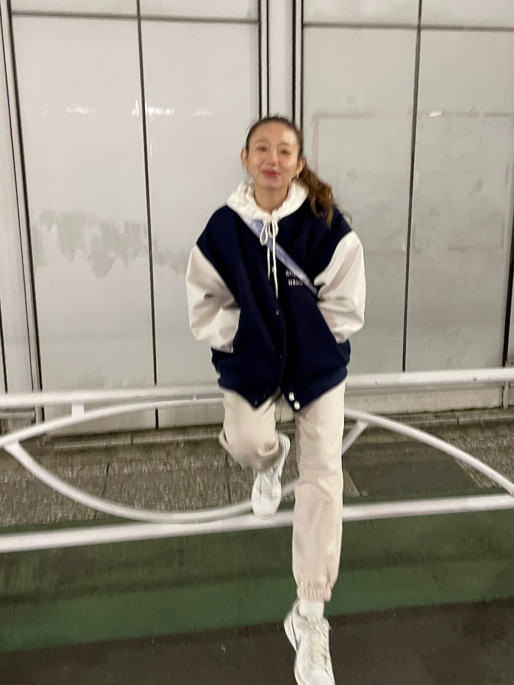 ブルー系のスタジャン、ブルー系のショルダーバッグ、ベージュ系のパンツを着用したレディースの秋コーディネートの2枚目の写真