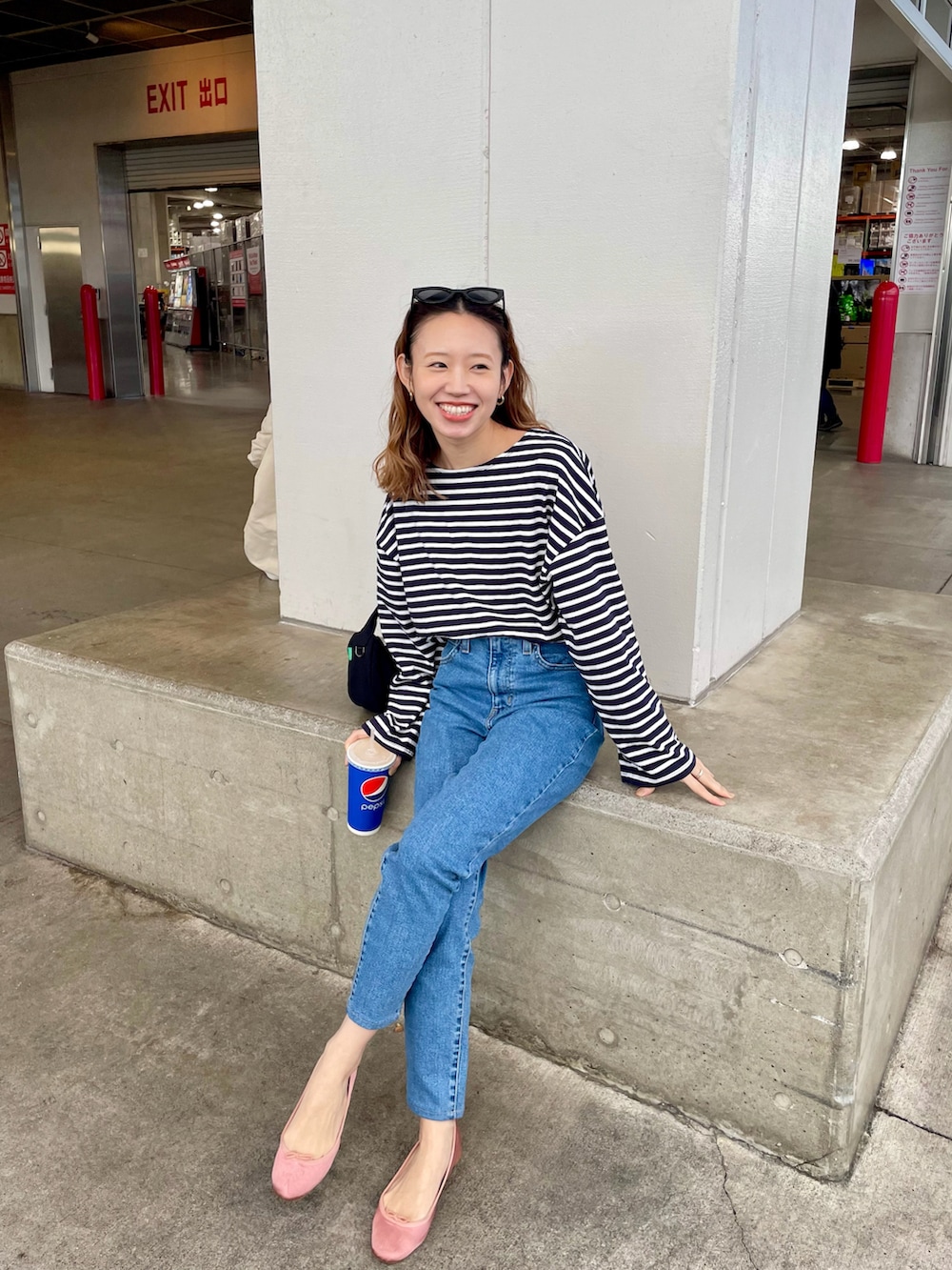 ブルー系のデニムパンツ、ブラック系のハンドバッグ、ピンク系のバレエシューズを着用したレディースの冬コーディネートの2枚目の写真