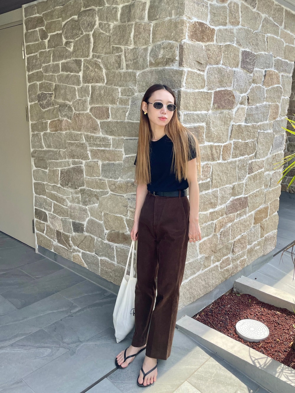 ブラック系のTシャツ/カットソー、ブラウン系のパンツ、ブラック系のサンダルを着用したレディースの夏コーディネートの2枚目の写真