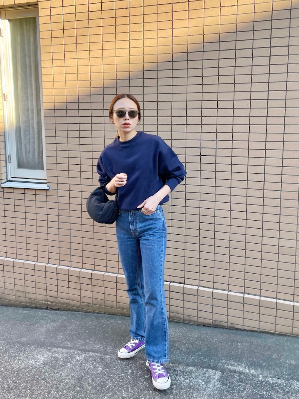 ブルー系のスウェット、ブルー系のデニムパンツ、ブラック系のハンドバッグを着用したレディースの秋コーディネートの2枚目の写真