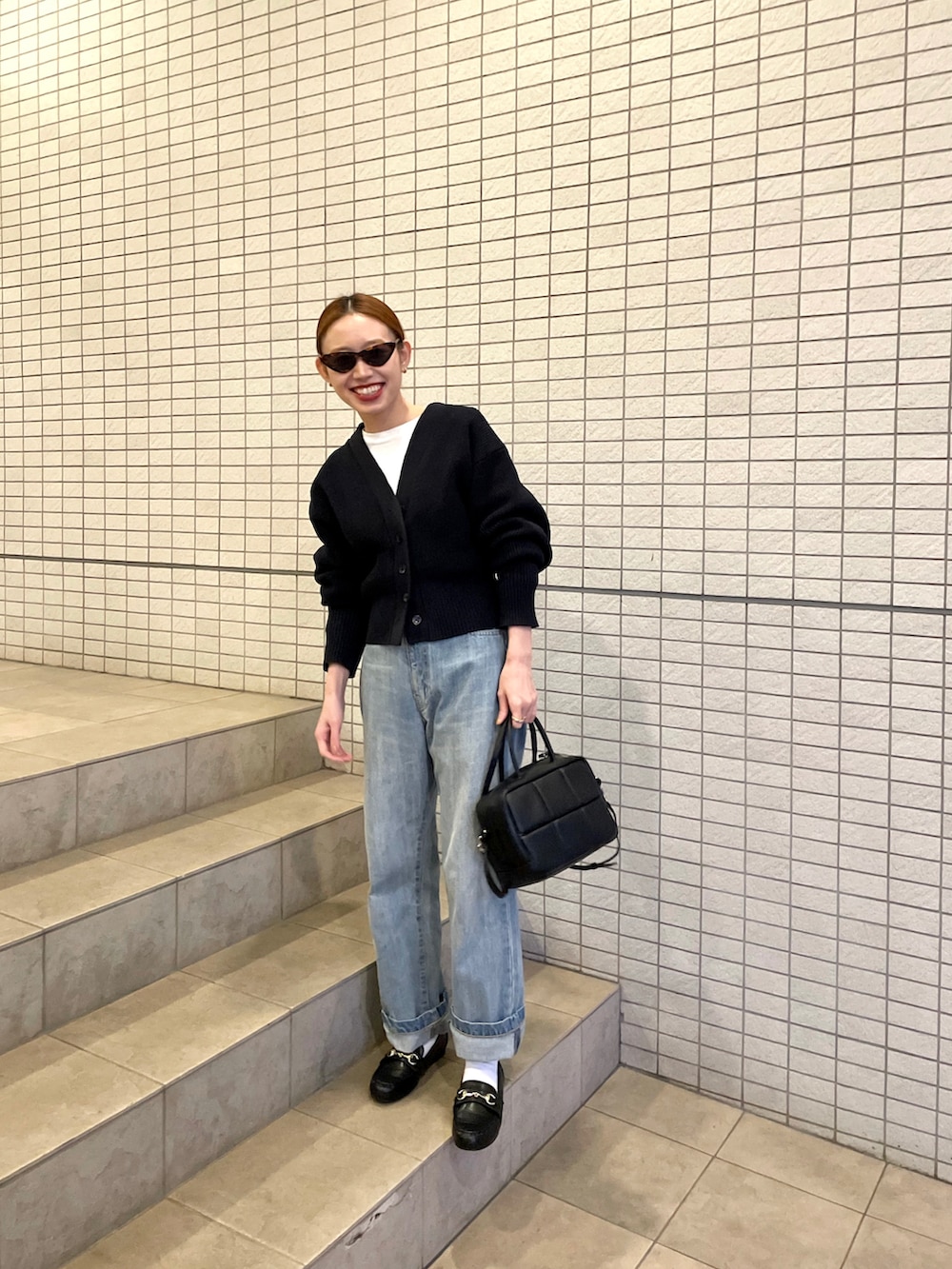 ブルー系のカーディガン/ボレロ、ブルー系のデニムパンツ、ブラック系のボストンバッグを着用したレディースの冬コーディネートの2枚目の写真