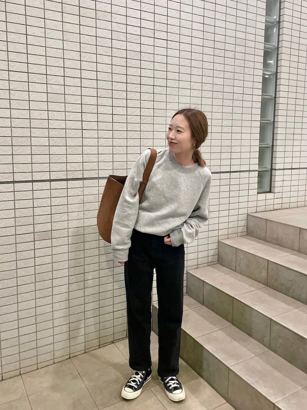 グレー系のスウェット、ブラック系のデニムパンツを着用したレディースの秋コーディネートの2枚目の写真