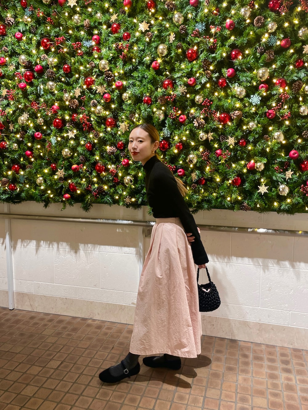 ピンク系のスカート、ブラック系のハンドバッグを着用したレディースの冬コーディネートの2枚目の写真