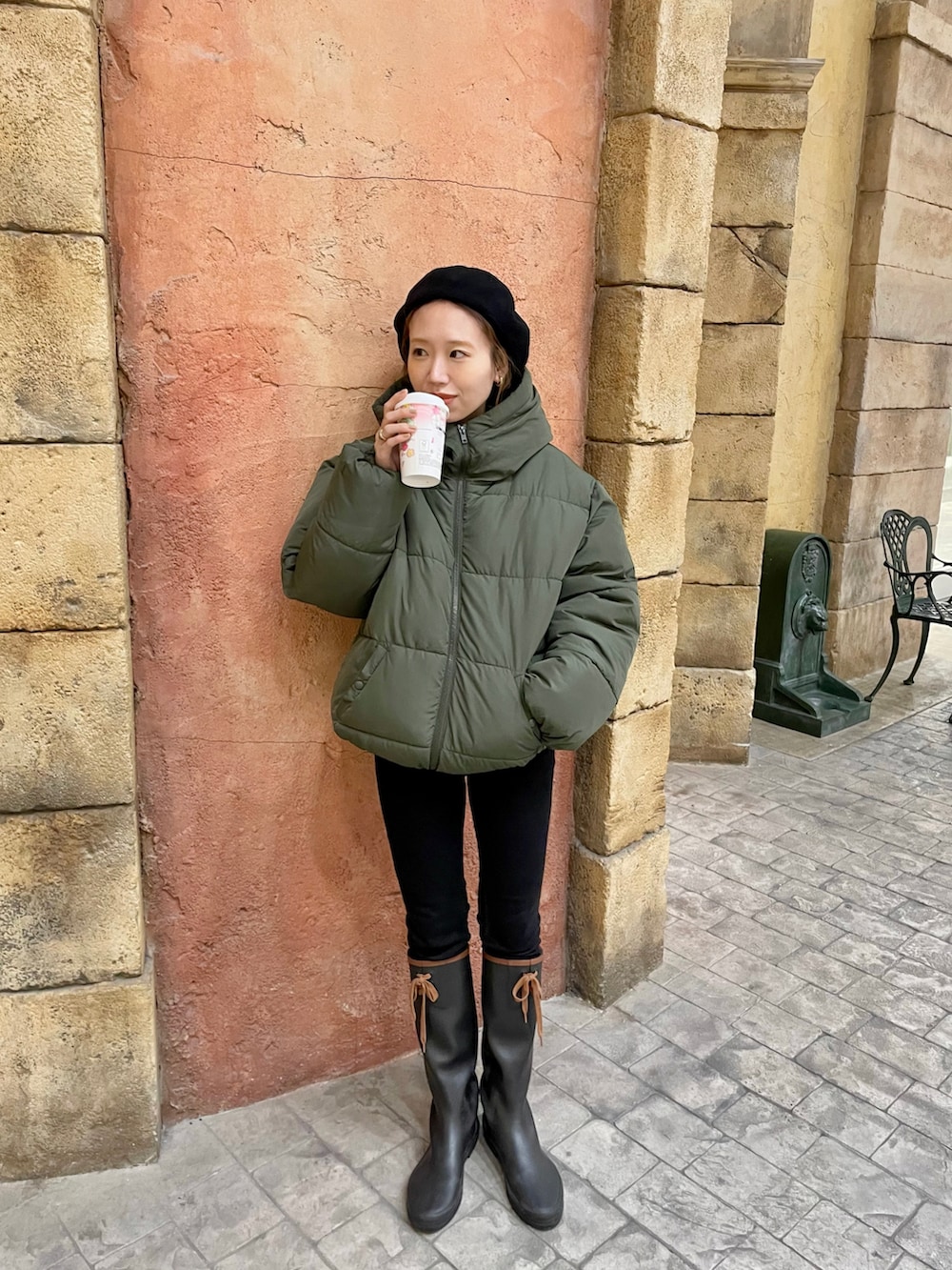 グリーン系のブルゾン、ブラック系のレインシューズ、ブラック系のハンチング/ベレー帽を着用したレディースの冬コーディネートの2枚目の写真