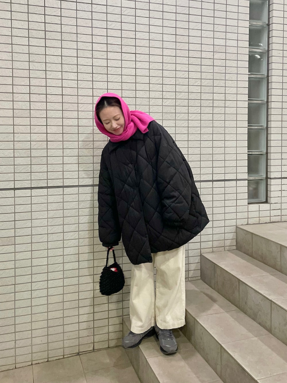 ブラック系のダウンジャケット/コート、グレー系のスニーカー、ピンク系のマフラーを着用したレディースの冬コーディネートの2枚目の写真
