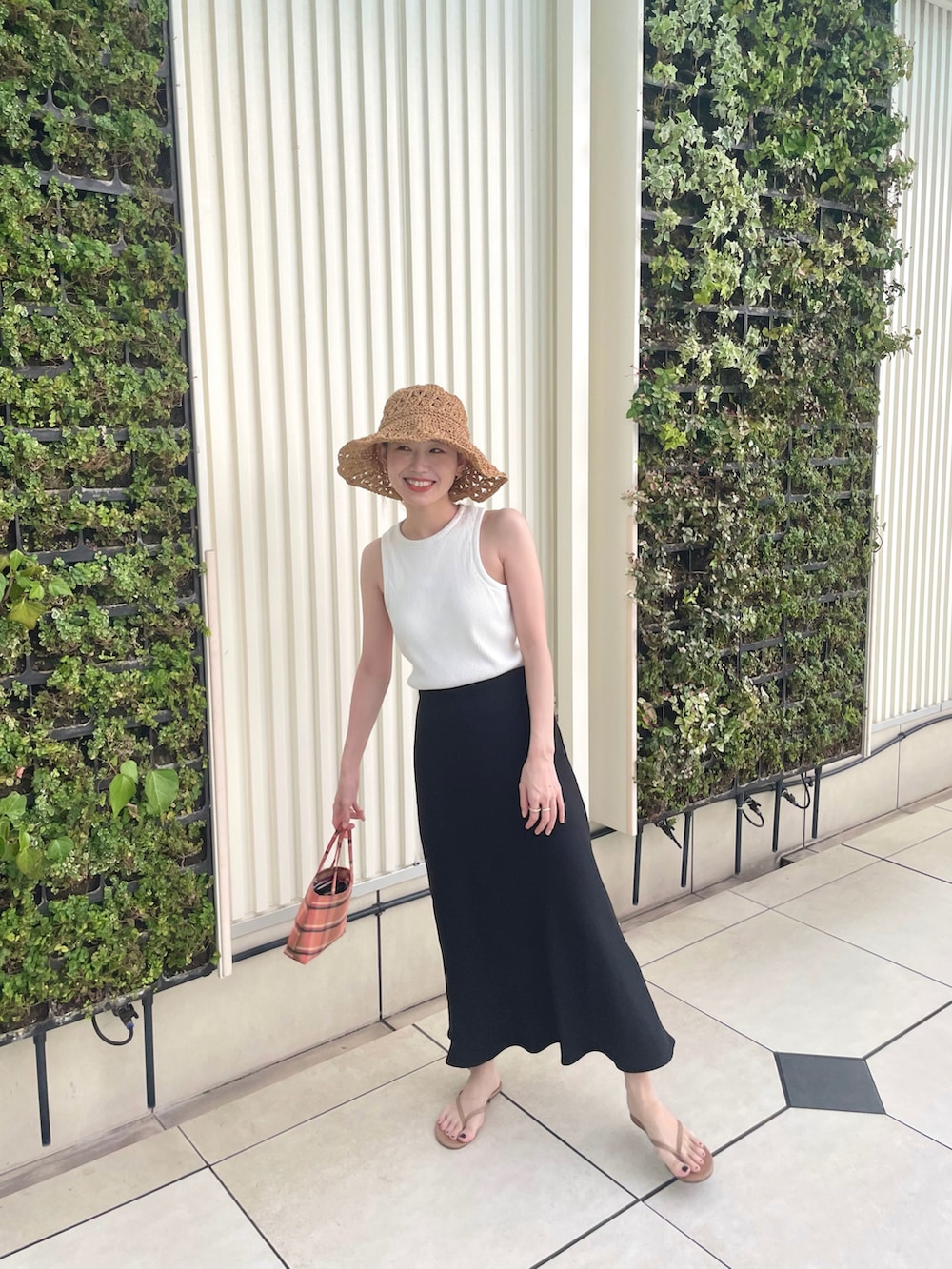 ホワイト系のタンクトップ、ブラック系のスカート、その他のトートバッグを着用したレディースの夏コーディネートの2枚目の写真