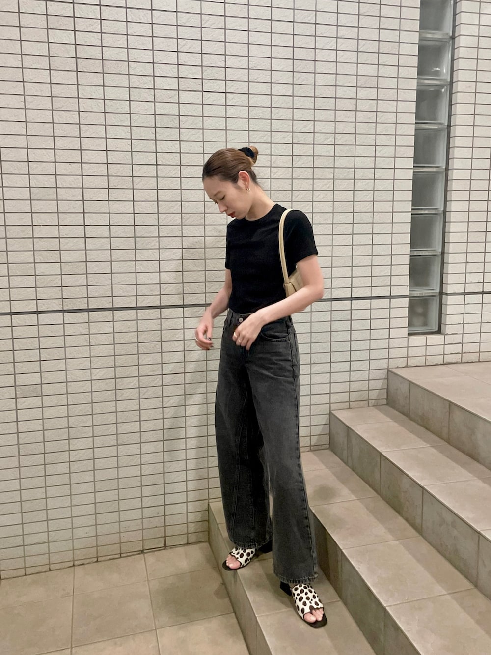 ブラック系のTシャツ/カットソー、ブラック系のデニムパンツ、ベージュ系のショルダーバッグを着用したレディースの春コーディネートの2枚目の写真