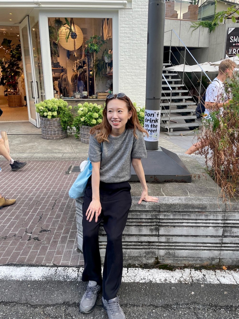 グレー系のニット/セーター、ブラック系のスラックス、グレー系のスニーカーを着用したレディースの秋コーディネートの2枚目の写真