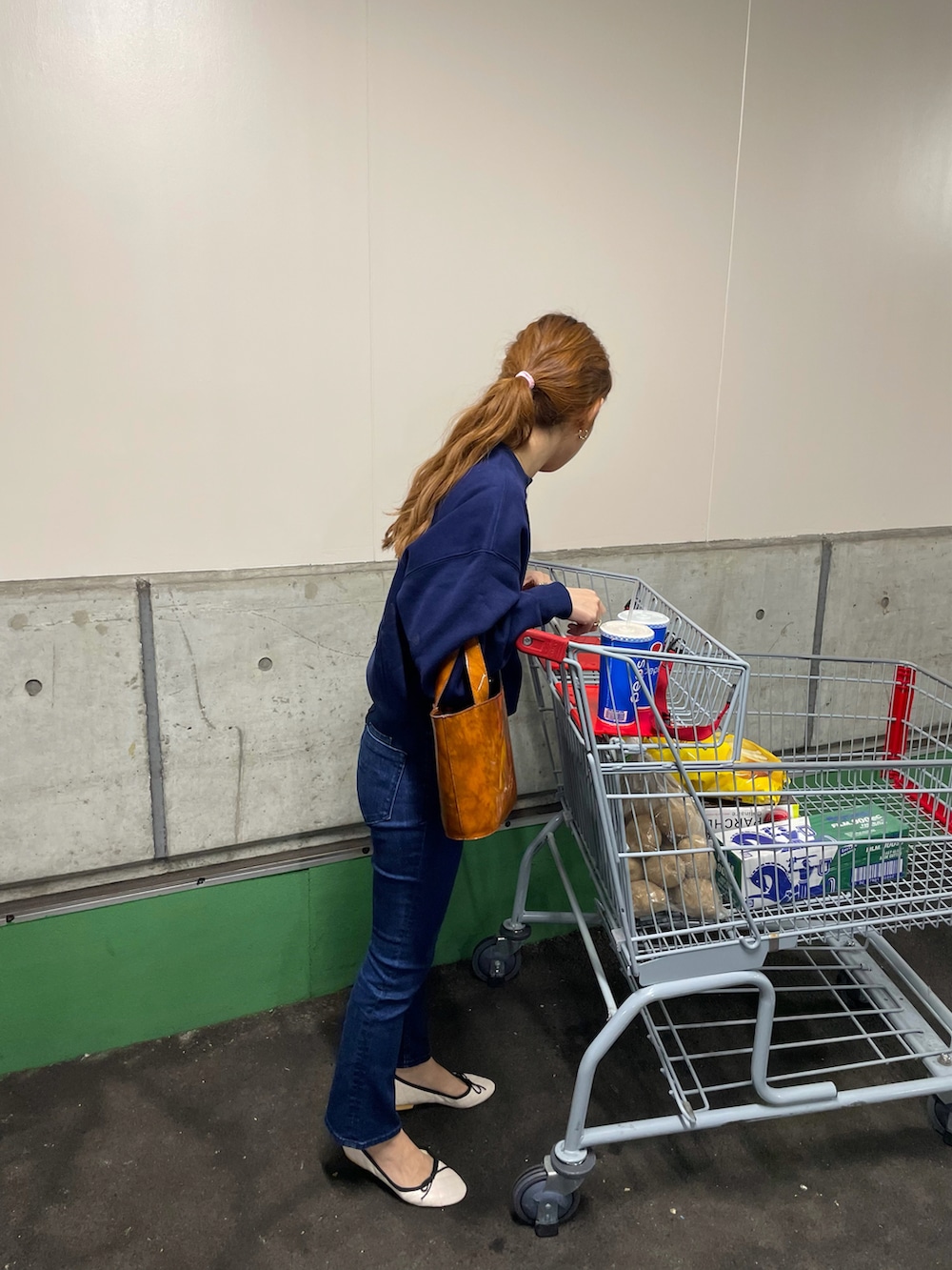 ブルー系のスウェット、ブルー系のデニムパンツ、ブラウン系のバッグを着用したレディースの秋コーディネートの3枚目の写真