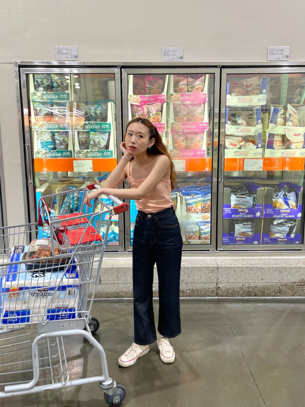 オレンジ系のキャミソール、ブルー系のデニムパンツを着用したレディースの夏コーディネートの2枚目の写真