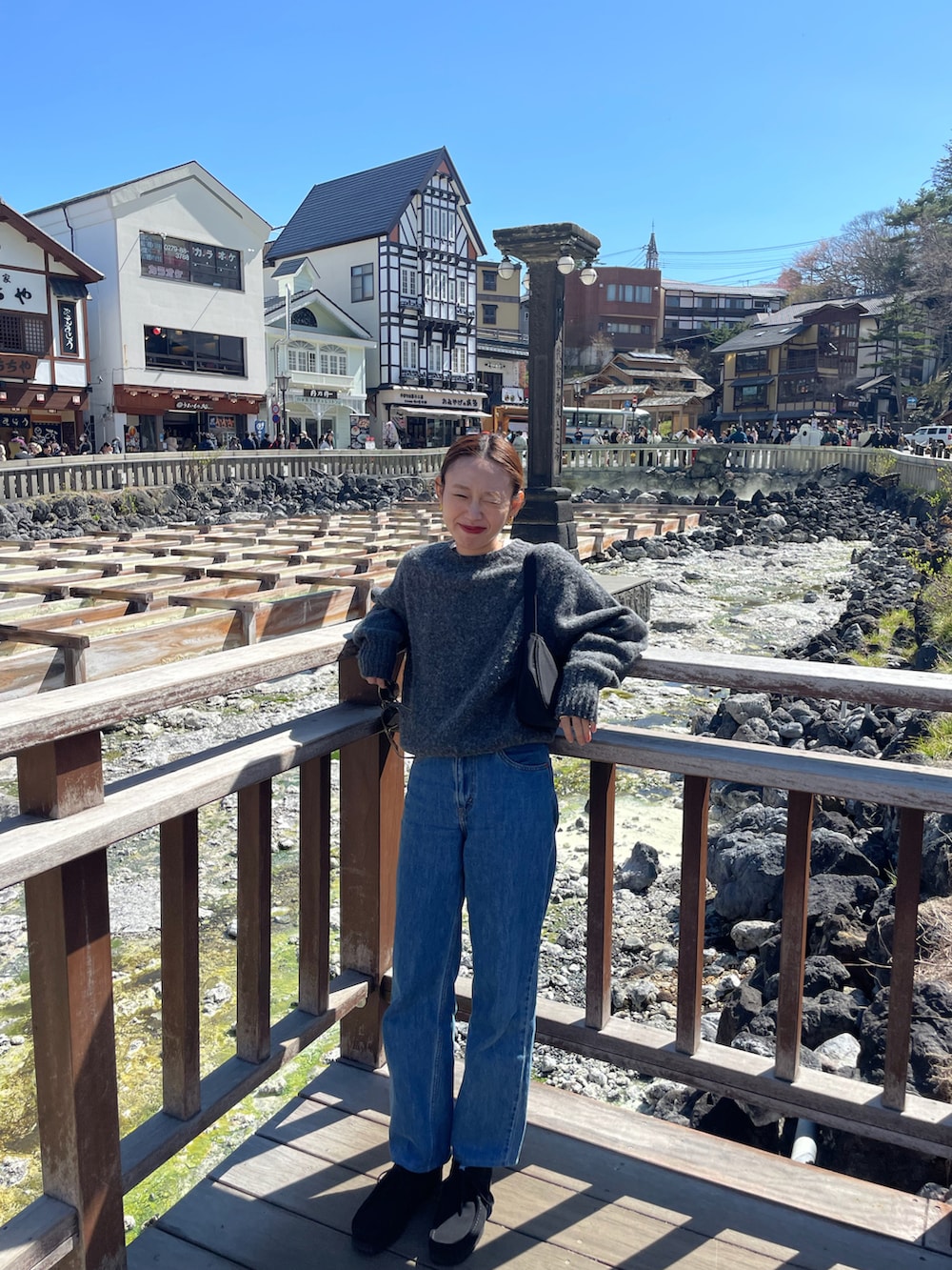 グレー系のニット/セーター、ブルー系のデニムパンツ、ブラック系のシューズを着用したレディースの春コーディネートの2枚目の写真