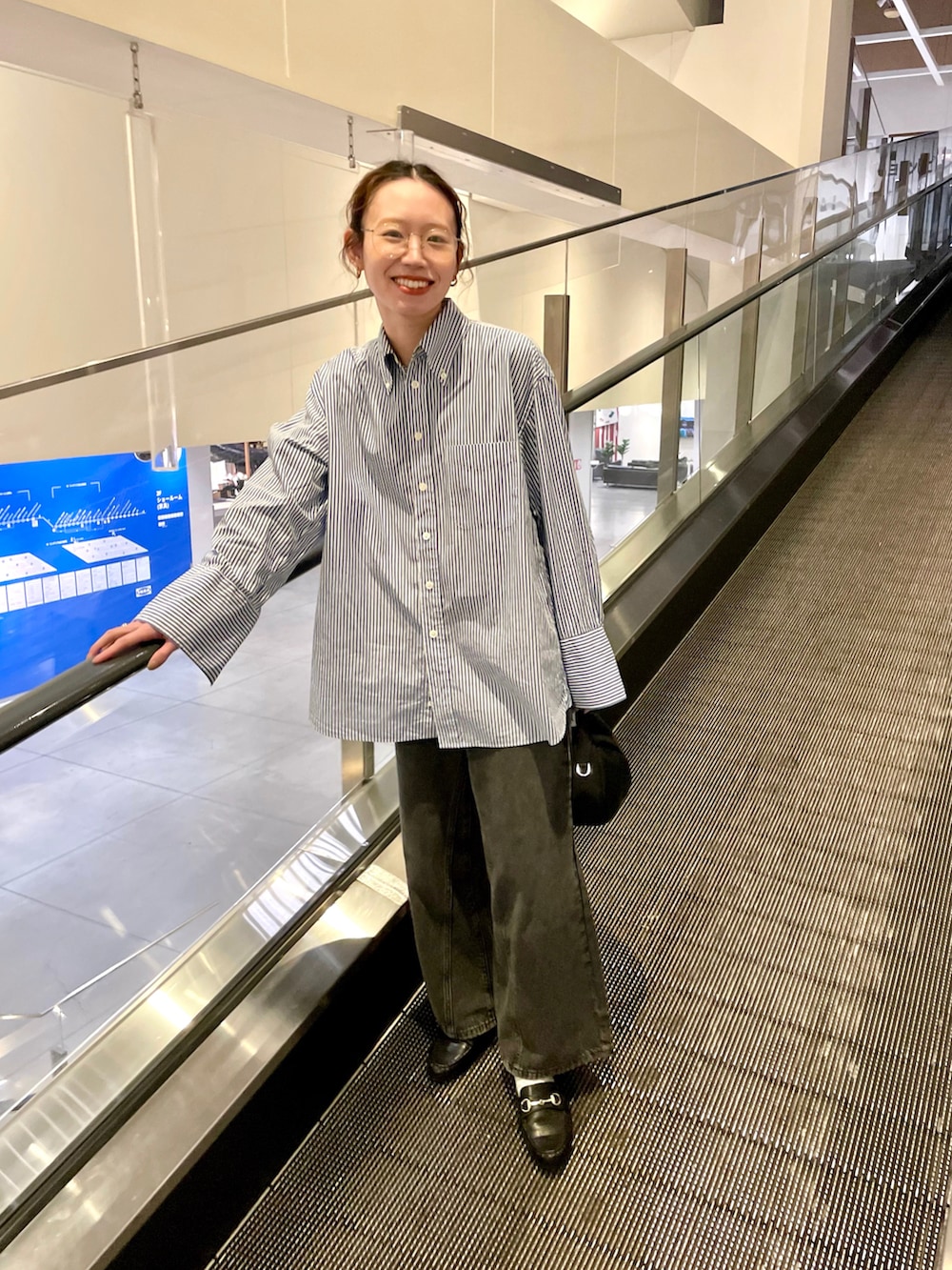 ブラック系のデニムパンツ、ブルー系のシャツ/ブラウス、ブラック系のローファーを着用したレディースの冬コーディネートの2枚目の写真