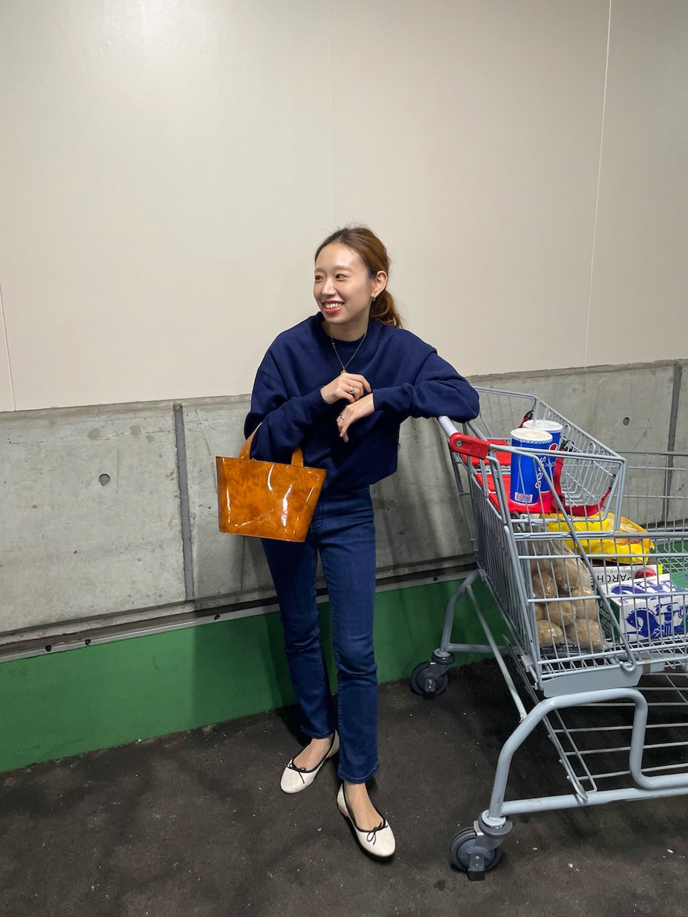 ブルー系のスウェット、ブルー系のデニムパンツ、ブラウン系のバッグを着用したレディースの秋コーディネートの2枚目の写真