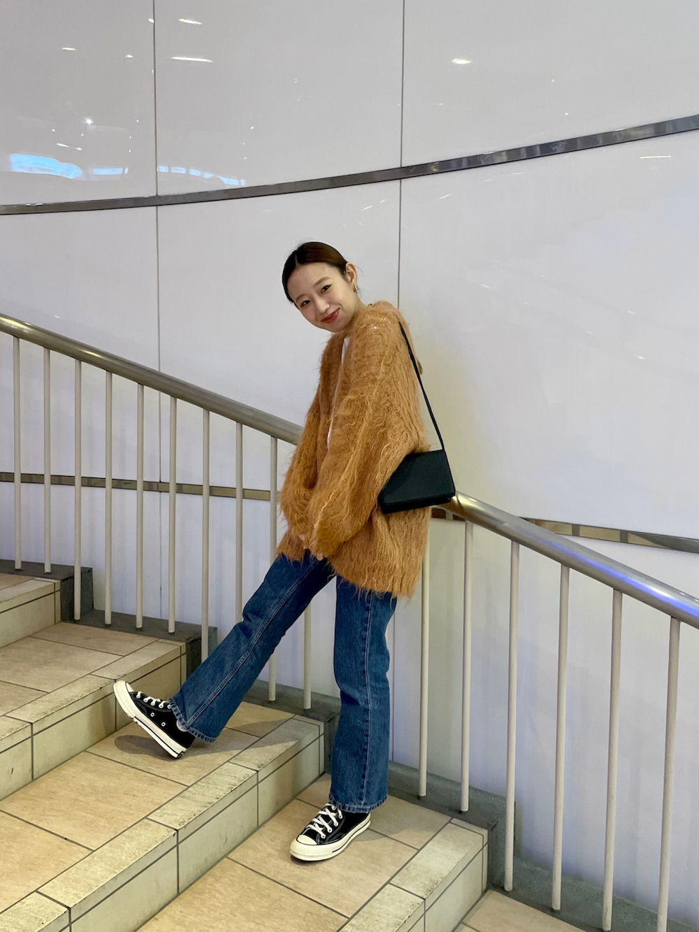 イエロー系のカーディガン/ボレロ、ブラック系のショルダーバッグ、ブルー系のデニムパンツを着用したレディースの秋コーディネートの2枚目の写真