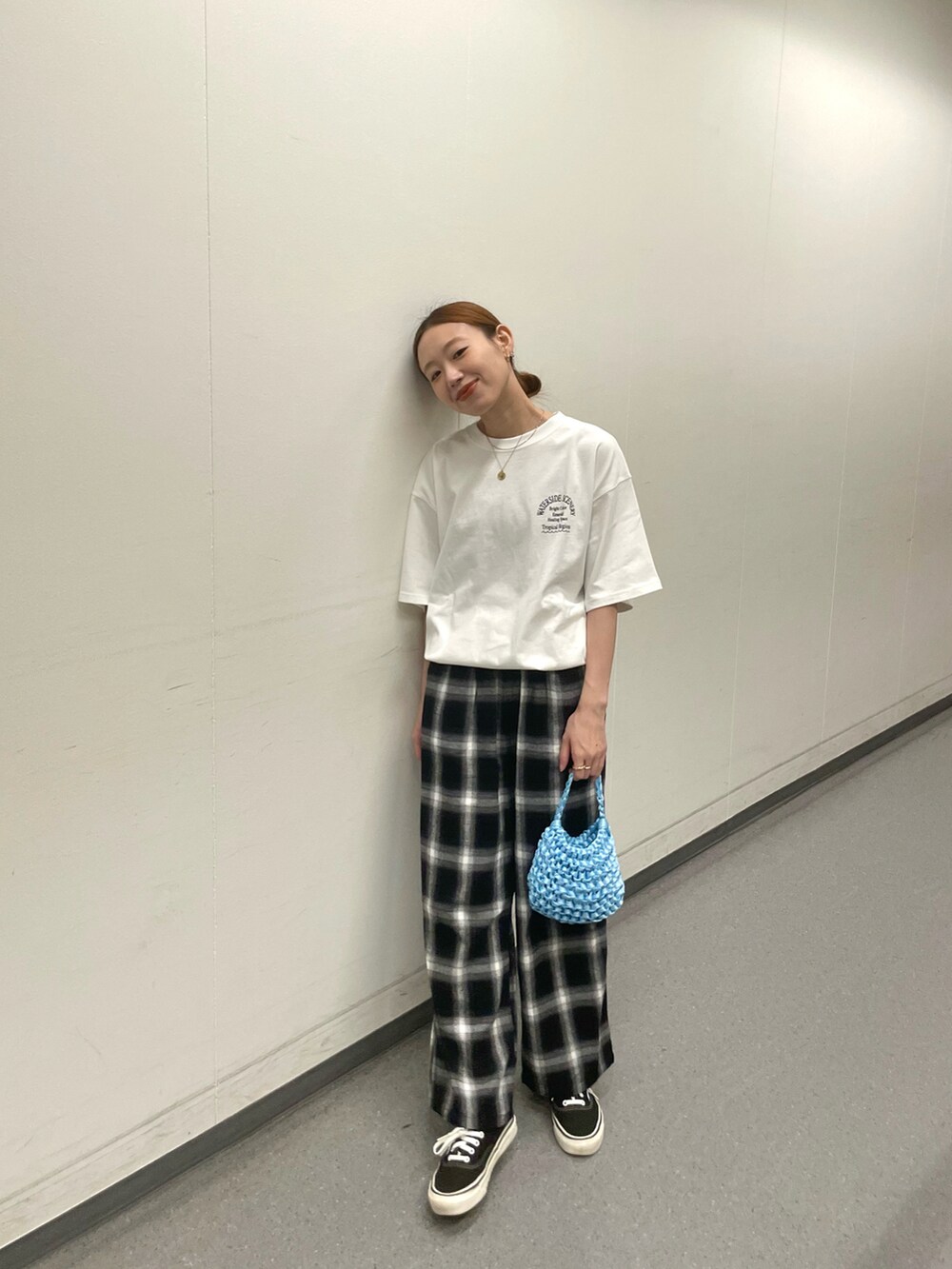 ホワイト系のTシャツ/カットソー、ブルー系のハンドバッグ、ブラック系のスニーカーを着用したレディースの夏コーディネートの2枚目の写真