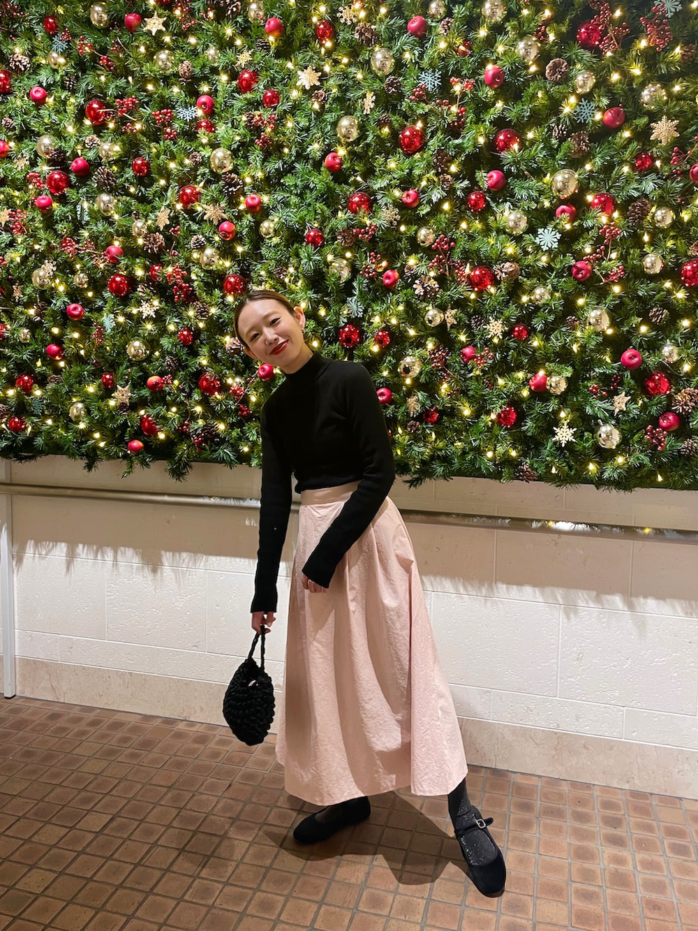 ピンク系のスカート、ブラック系のハンドバッグを着用したレディースの冬コーディネートの3枚目の写真