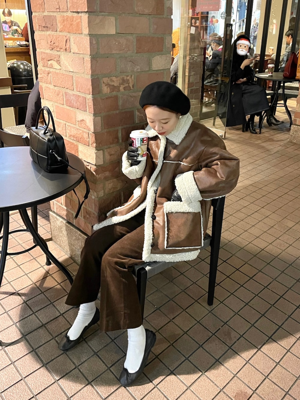ブラウン系のムートンコート、ブラウン系のパンツ、ブラック系のバレエシューズを着用したレディースの秋コーディネートの2枚目の写真