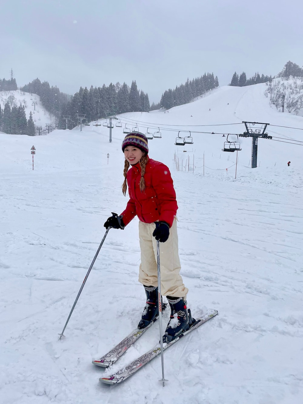 レッド系のダウンジャケット/コート、ホワイト系のスラックスを着用したレディースの冬コーディネートの2枚目の写真