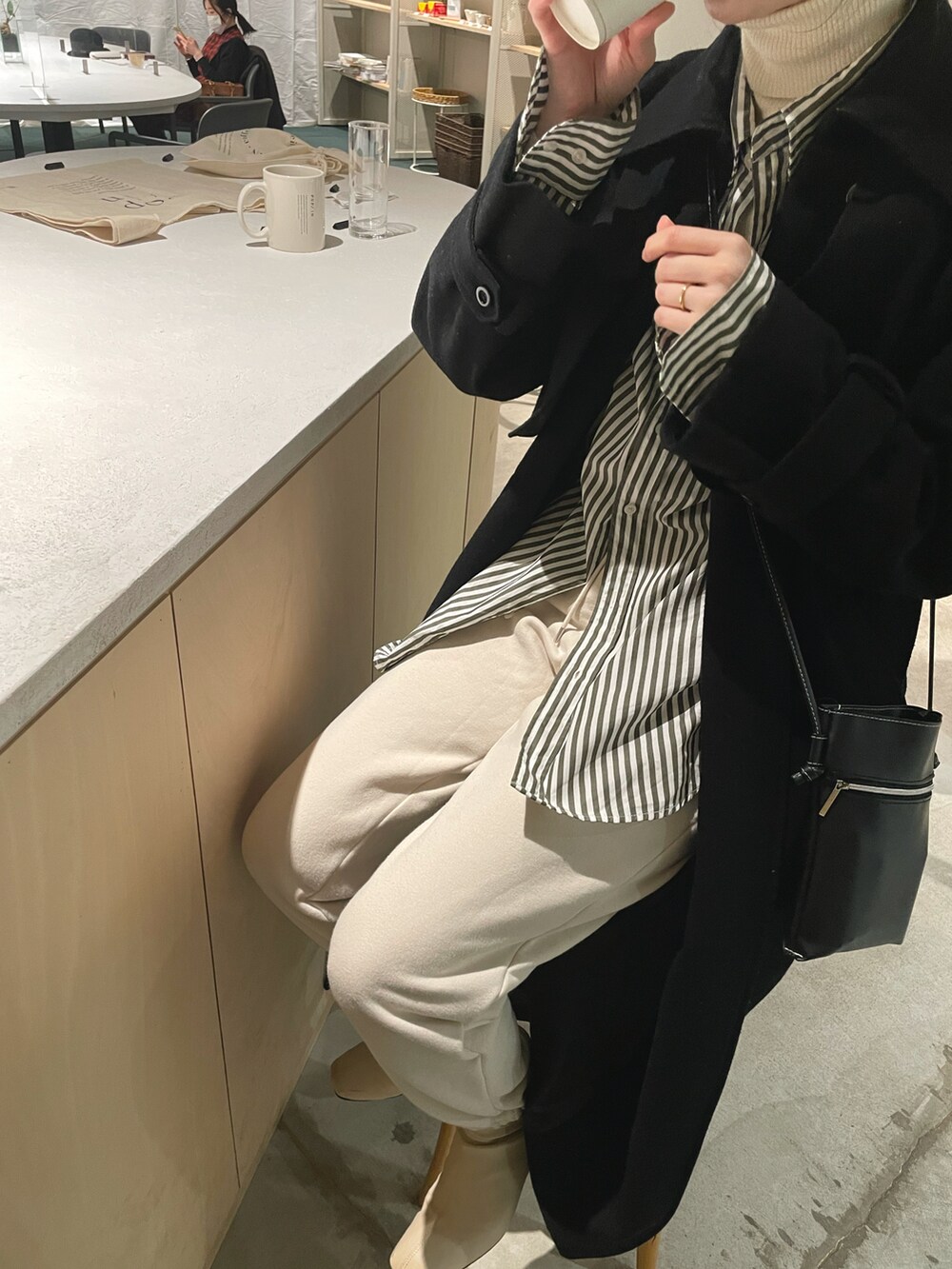 ホワイト系のニット/セーター、ブルー系のシャツ/ブラウス、ベージュ系のパンツを着用したレディースの冬コーディネートの2枚目の写真