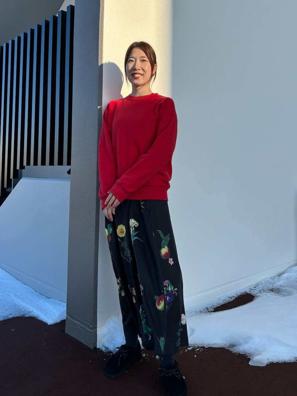 レッド系のスウェット、ブラック系のワンピース、ブラック系のブーツを着用したレディースの冬コーディネートの2枚目の写真