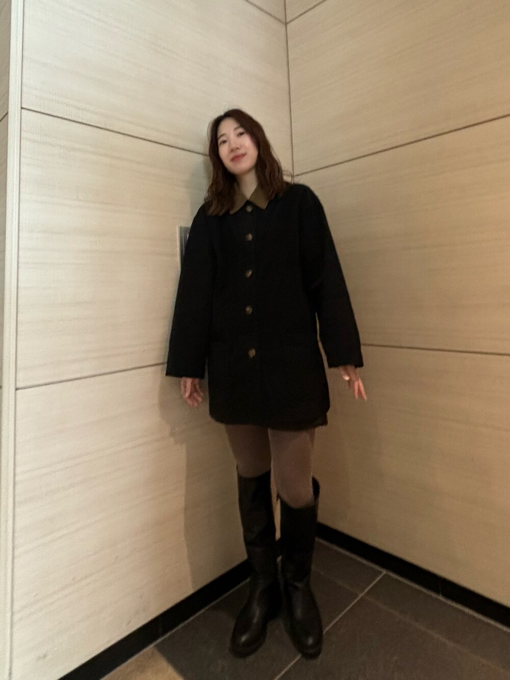 ブラック系のジャケット/アウター、ブラック系のブーツ、ブラウン系のタイツ/ストッキングを着用したレディースの冬コーディネートの2枚目の写真