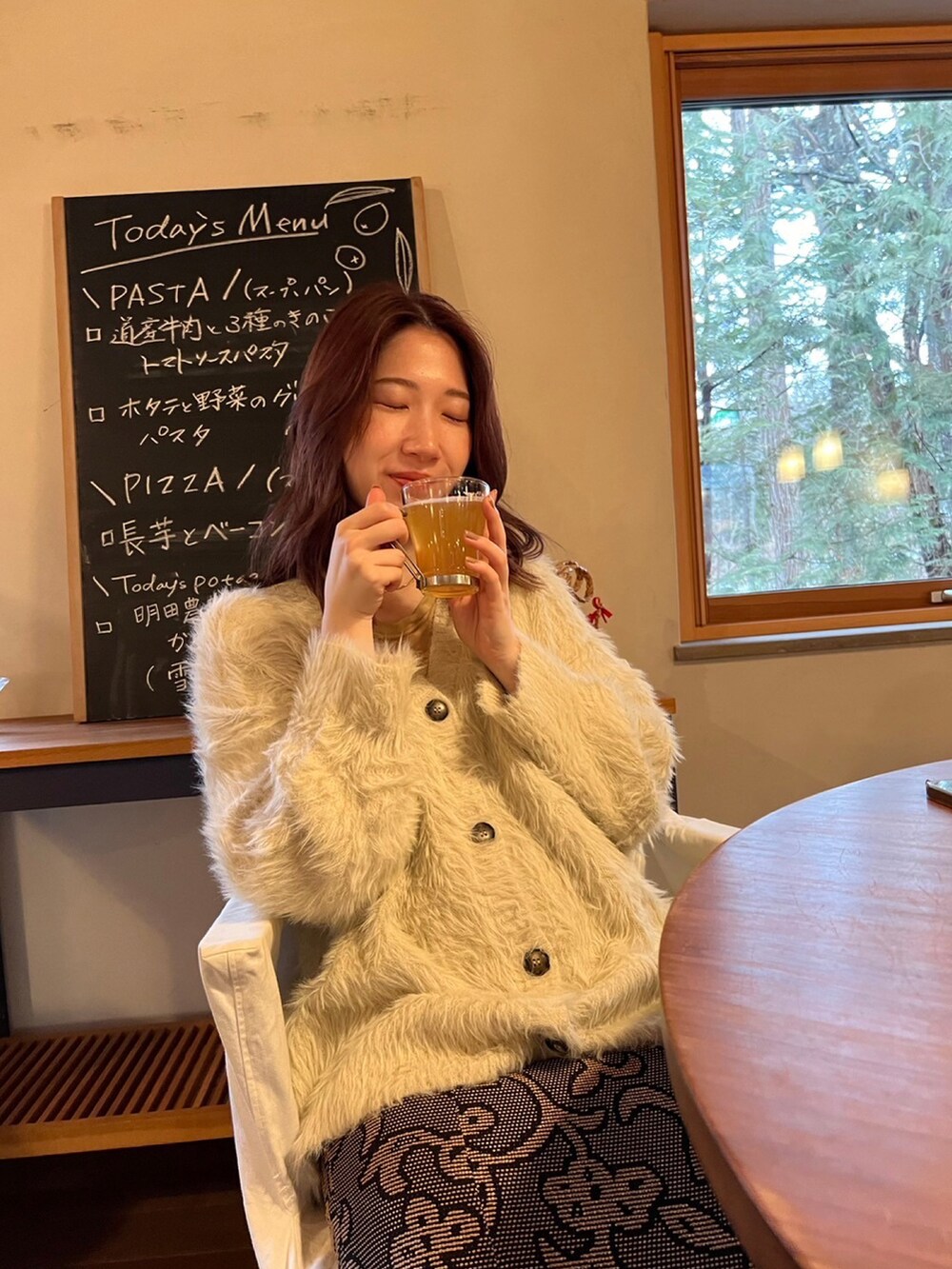 ホワイト系のカーディガン/ボレロ、ブラック系のスカートを着用したレディースの冬コーディネートの2枚目の写真