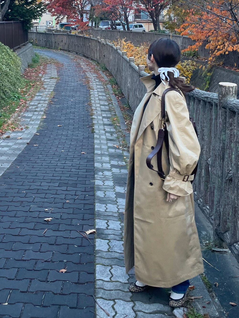 ベージュ系のトレンチコート、ブルー系のデニムパンツ、その他のバレエシューズを着用したレディースの秋コーディネートの2枚目の写真