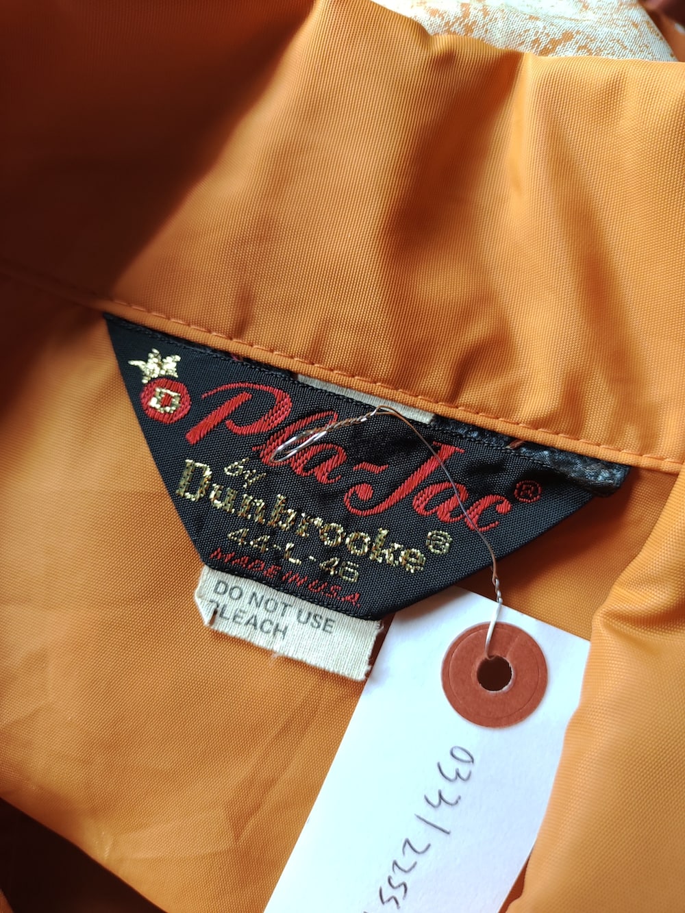 オレンジ系のナイロンジャケットを着用したメンズの春コーディネートの3枚目の写真