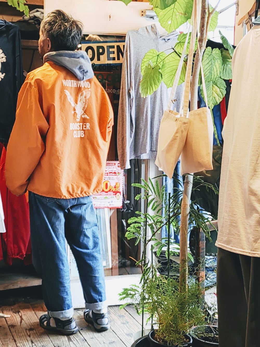 オレンジ系のナイロンジャケットを着用したメンズの春コーディネートの2枚目の写真