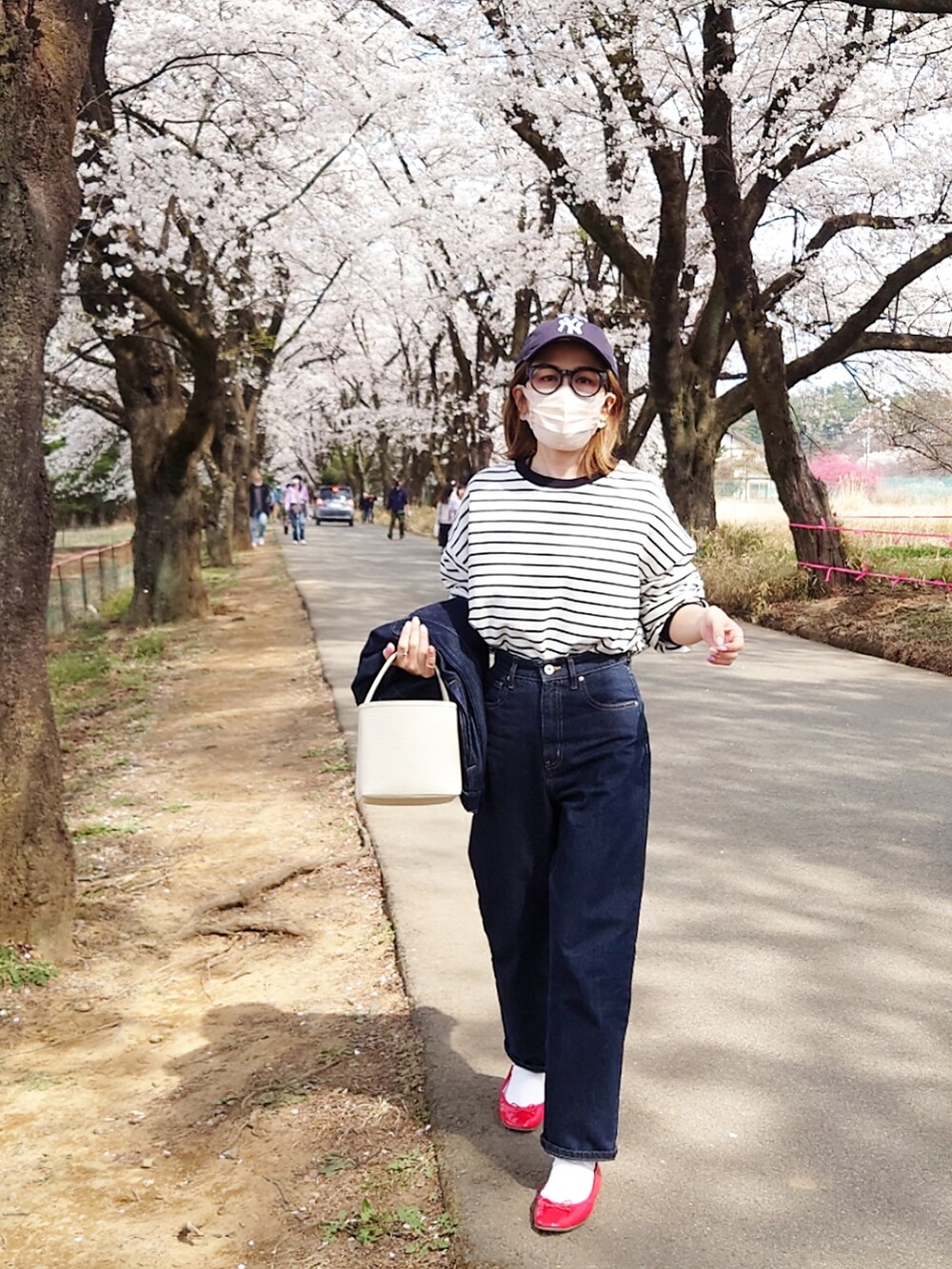 ブラック系のTシャツ/カットソー、ブルー系のデニムパンツ、ホワイト系のハンドバッグを着用したレディースの春コーディネートの4枚目の写真