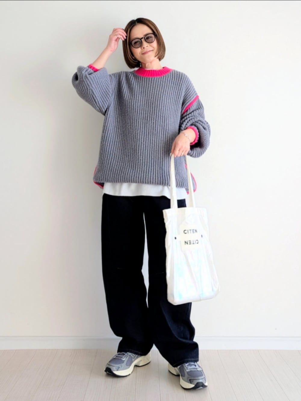 グレー系のニット/セーター、ホワイト系のトートバッグ、ブルー系のデニムパンツを着用したレディースの冬コーディネートの4枚目の写真