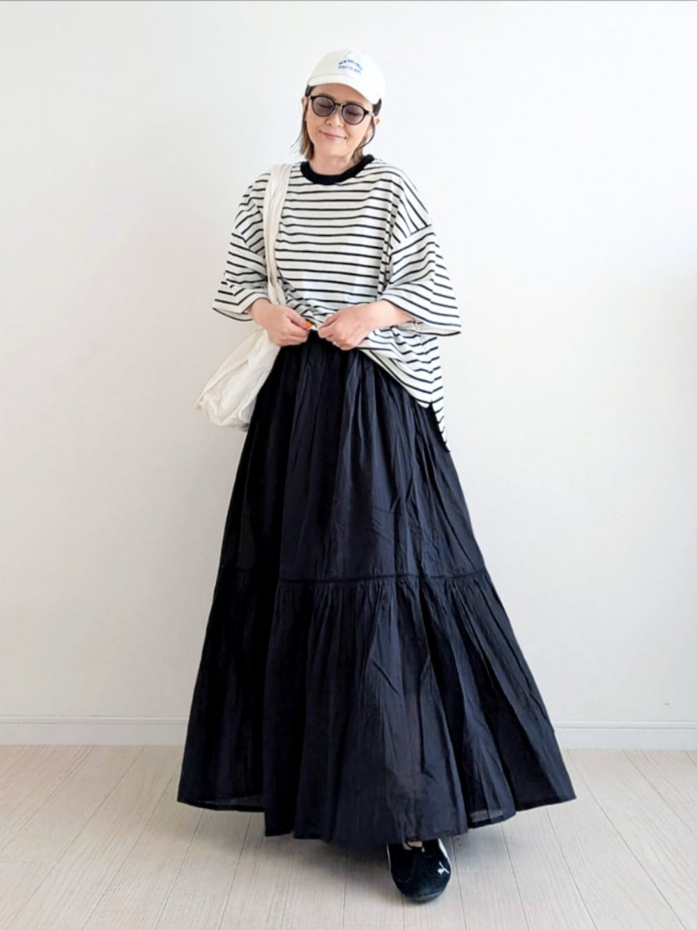 ブラック系のTシャツ/カットソー、ブラック系のスカート、ブラック系のスニーカーを着用したレディースの春コーディネートの4枚目の写真