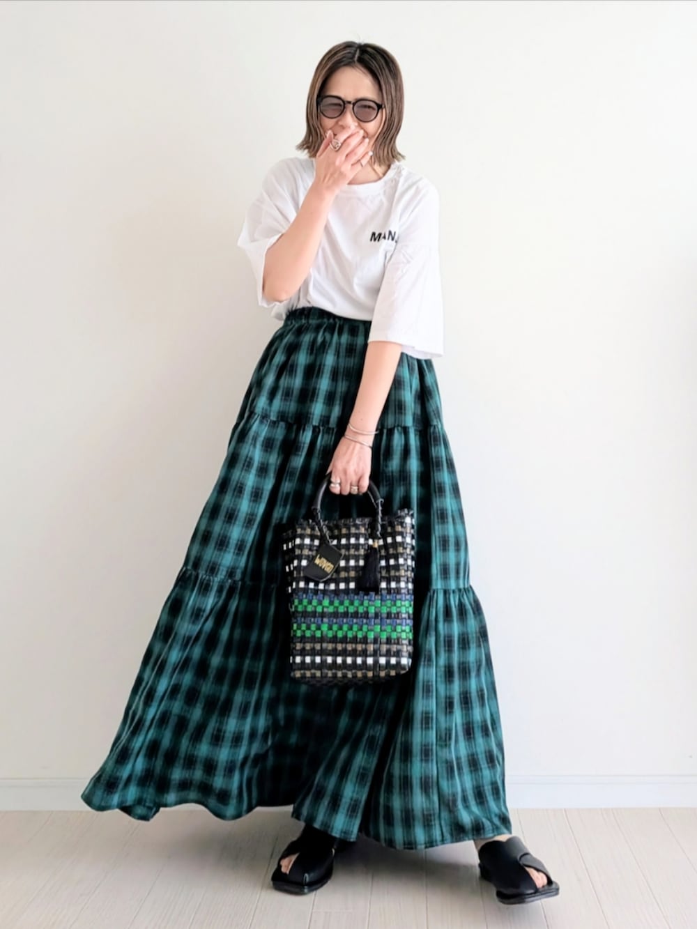 グリーン系のスカート、ブラック系のかごバッグ、ホワイト系のTシャツ/カットソーを着用したレディースの春コーディネートの3枚目の写真