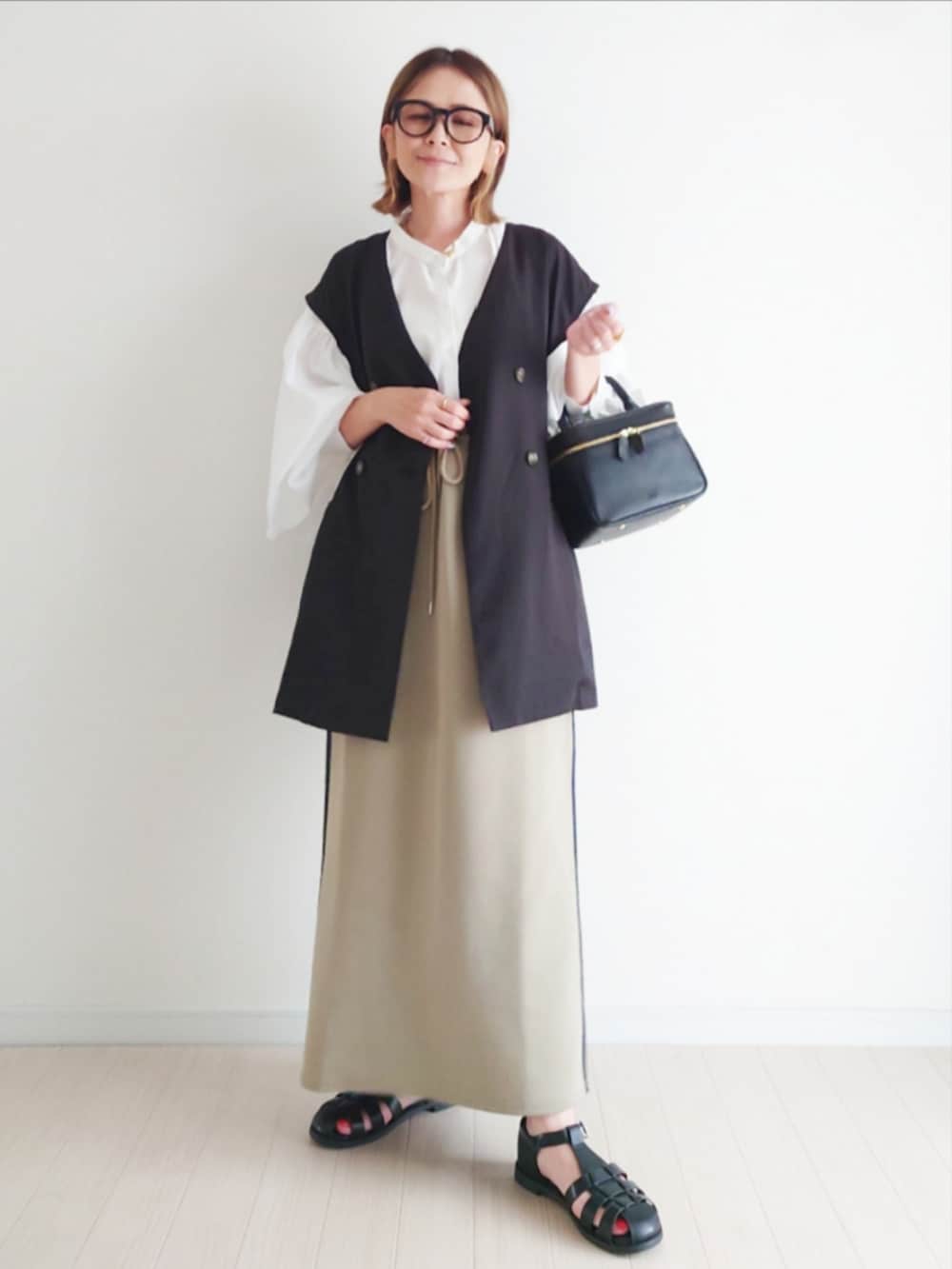 ブルー系のスカート、ホワイト系のシャツ/ブラウス、ブラック系のベストを着用したレディースの春コーディネートの2枚目の写真