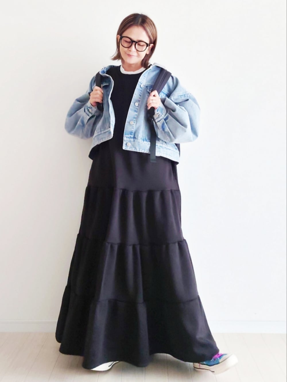 ブルー系のデニムジャケット、ブラック系のバックパック/リュック、ブラック系のワンピースを着用したレディースの冬コーディネートの5枚目の写真