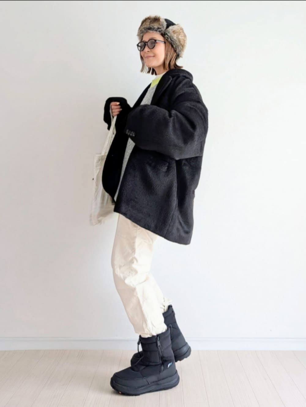 グレー系のニット/セーター、ブラック系のテーラードジャケット、ブラック系のブーツを着用したレディースの冬コーディネートの3枚目の写真