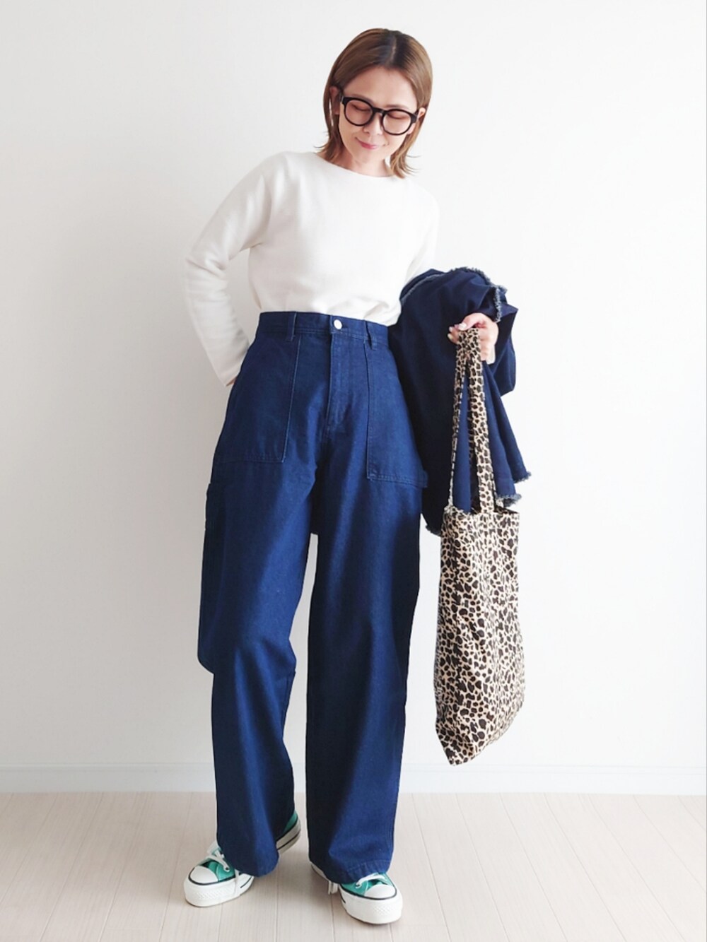 ブルー系のデニムジャケット、ホワイト系のニット/セーター、グリーン系のスニーカーを着用したレディースの春コーディネートの3枚目の写真