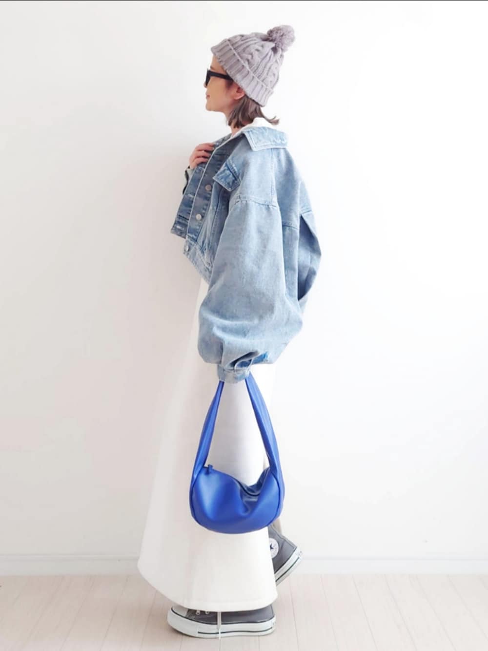 ブルー系のデニムジャケット、ホワイト系のスカート、ブルー系のハンドバッグを着用したレディースの冬コーディネートの2枚目の写真