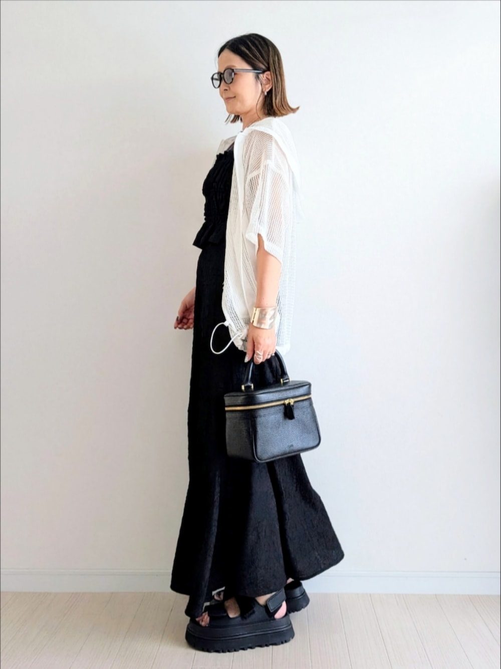 ブラック系のサンダル、ブラック系のワンピース、ホワイト系のパーカーを着用したレディースの夏コーディネートの2枚目の写真