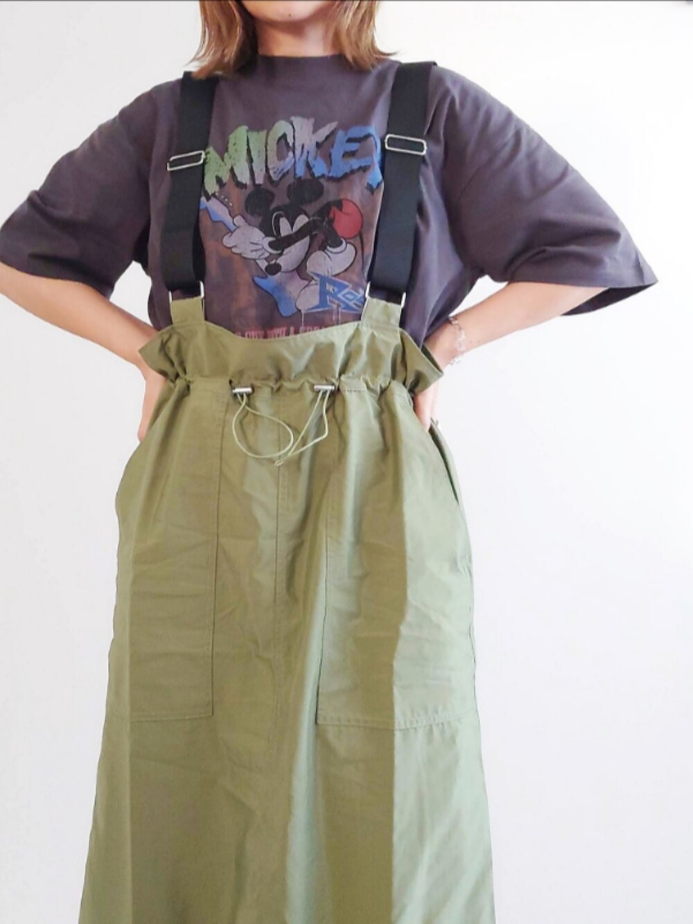 グレー系のTシャツ/カットソー、グリーン系のジャンパースカート、シルバー系のハンドバッグを着用したレディースの夏コーディネートの4枚目の写真