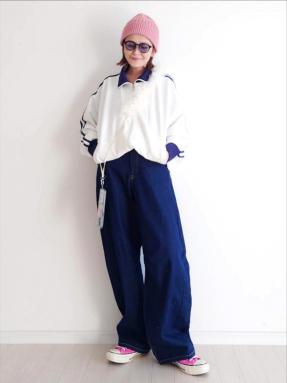 ホワイト系のジャージ、ブルー系のデニムパンツ、ピンク系のスニーカーを着用したレディースの冬コーディネートの2枚目の写真