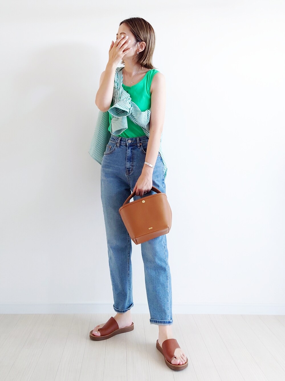 ブルー系のデニムパンツ、グリーン系のシャツ/ブラウス、ブラウン系のサンダルを着用したレディースの夏コーディネートの2枚目の写真