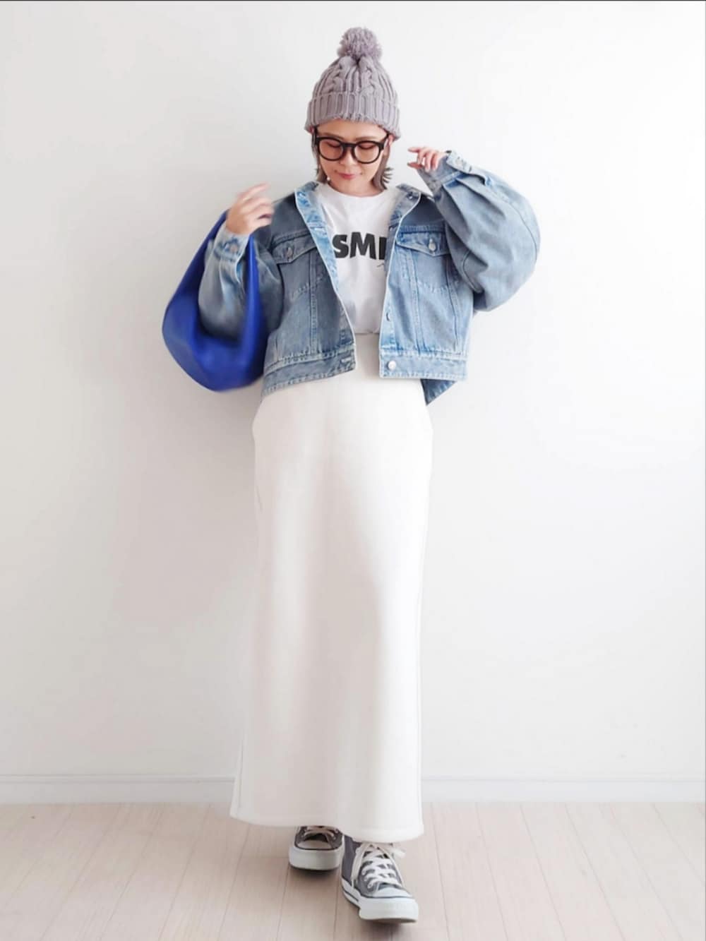 ブルー系のデニムジャケット、ホワイト系のスカート、ブルー系のハンドバッグを着用したレディースの冬コーディネートの3枚目の写真